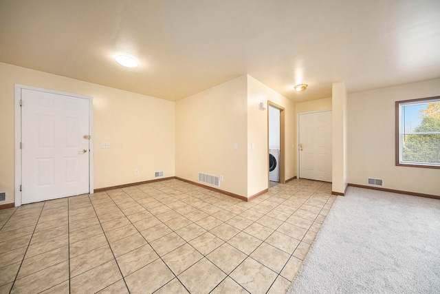 empty room with washer / dryer and light tile patterned floors