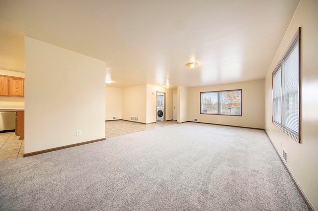 unfurnished living room with light carpet and washer / clothes dryer