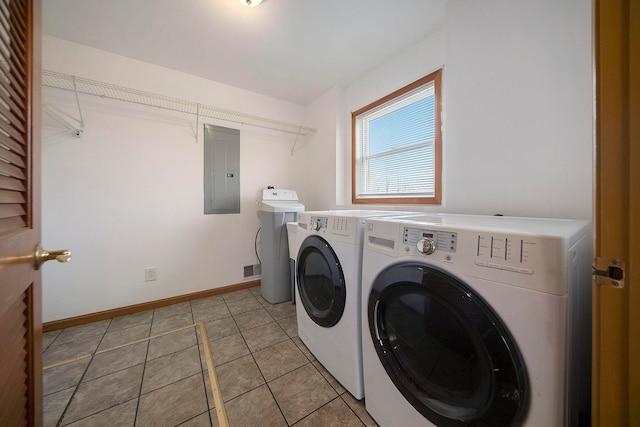 clothes washing area with light tile patterned floors, washing machine and dryer, and electric panel