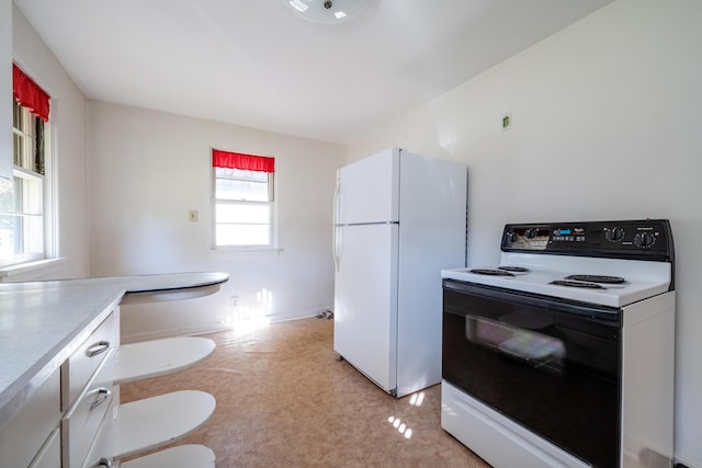 kitchen featuring white cabinets, white fridge, and electric range oven