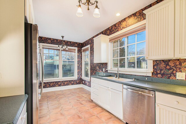 kitchen with decorative light fixtures, a notable chandelier, appliances with stainless steel finishes, light tile patterned flooring, and sink