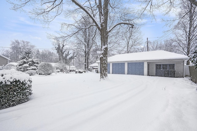 yard layered in snow with a garage and an outbuilding