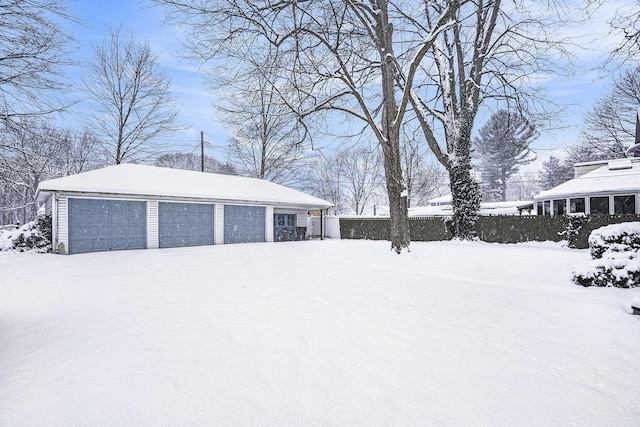 yard layered in snow with a garage and an outbuilding