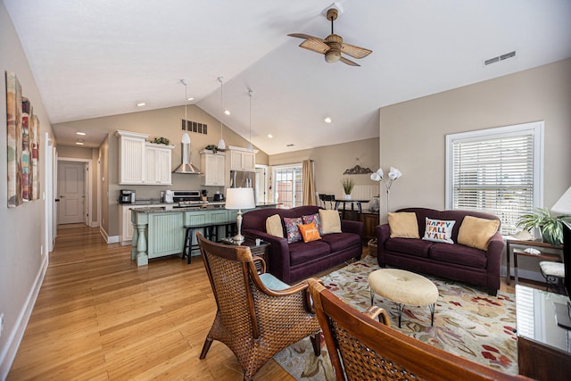 living room with light hardwood / wood-style floors, ceiling fan, plenty of natural light, and vaulted ceiling