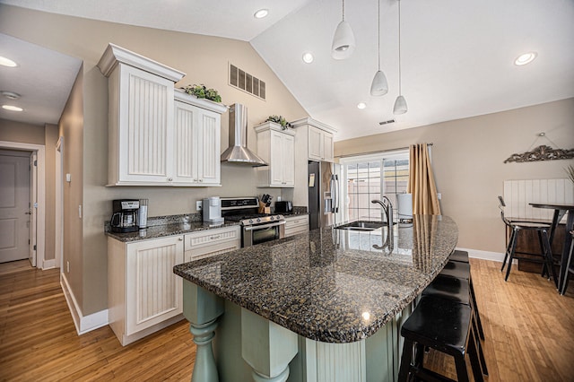 kitchen with wall chimney range hood, sink, white cabinetry, stainless steel appliances, and lofted ceiling