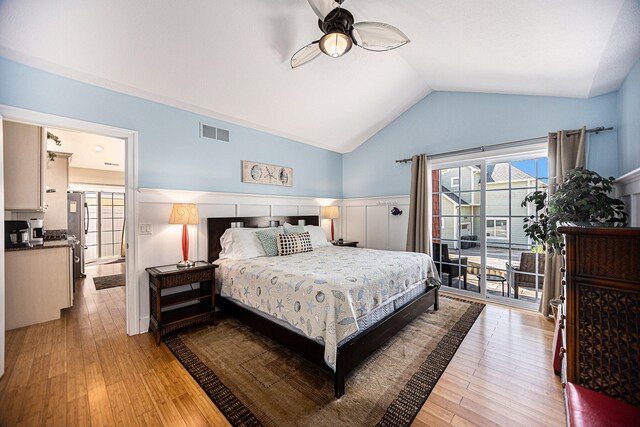 bedroom featuring stainless steel fridge, light wood-type flooring, and vaulted ceiling