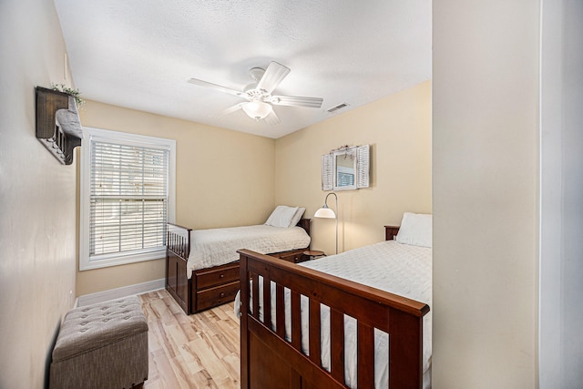 bedroom featuring a textured ceiling, light wood-type flooring, and ceiling fan