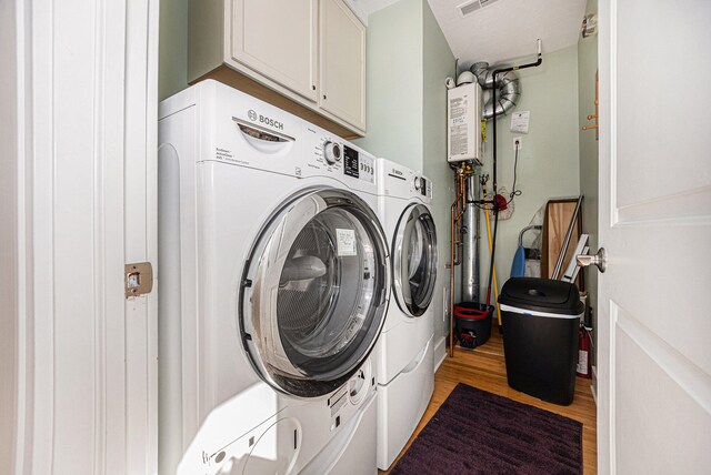 laundry area featuring cabinets, washing machine and clothes dryer, and hardwood / wood-style floors