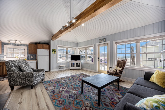 living room with light hardwood / wood-style floors, wood walls, and lofted ceiling with beams