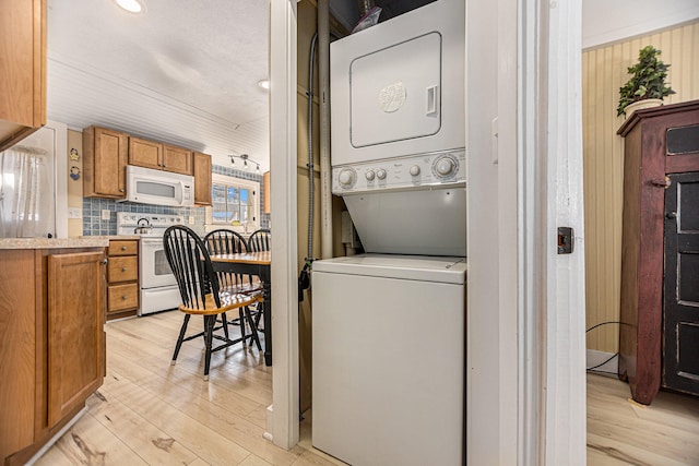 clothes washing area featuring stacked washing maching and dryer and light hardwood / wood-style floors