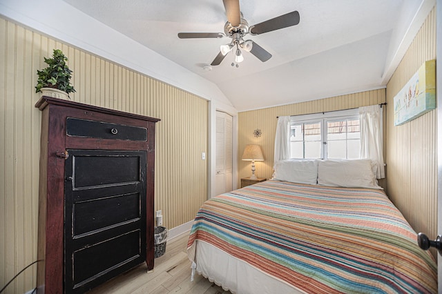 bedroom featuring lofted ceiling, a closet, light wood-type flooring, and ceiling fan