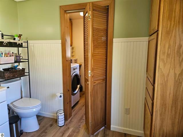 bathroom with toilet, washer / clothes dryer, and hardwood / wood-style floors