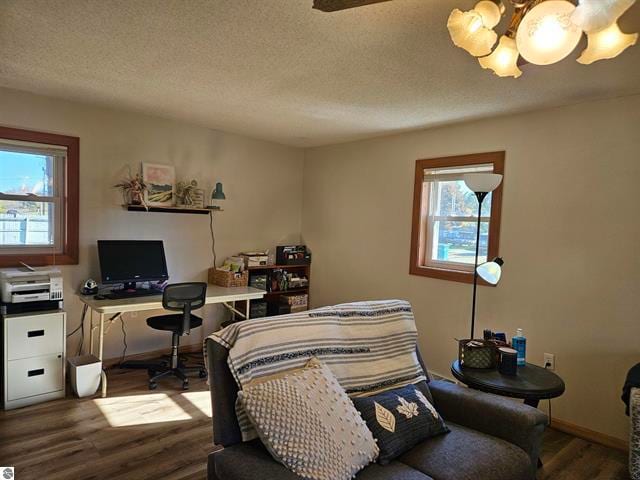 bedroom with hardwood / wood-style floors, a textured ceiling, and an inviting chandelier