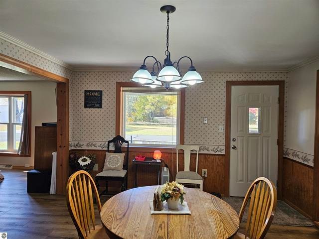 dining room featuring a notable chandelier, wooden walls, crown molding, and dark hardwood / wood-style flooring