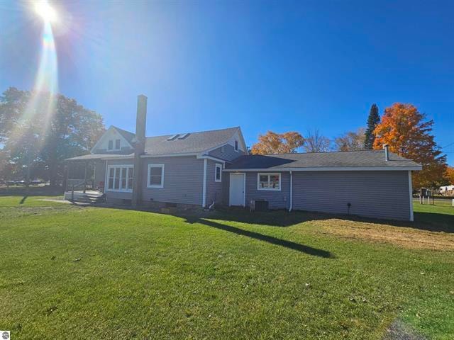 back of property with central air condition unit and a lawn