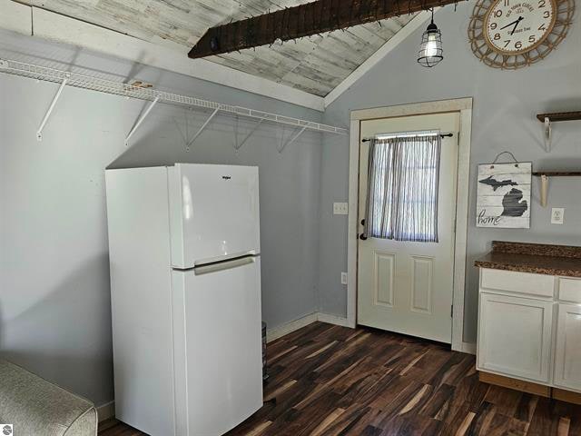 interior space featuring lofted ceiling with beams, wooden ceiling, white cabinets, dark wood-type flooring, and white refrigerator