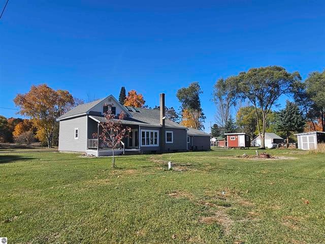 back of property with a storage unit and a lawn