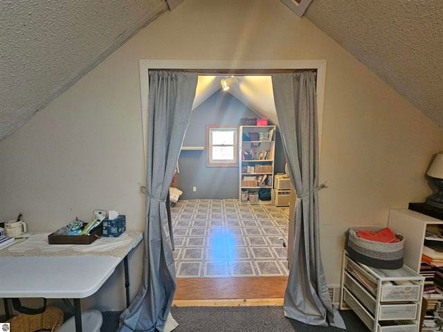 additional living space with a textured ceiling and vaulted ceiling