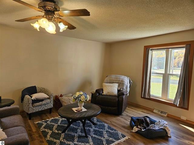 sitting room with ceiling fan, a textured ceiling, and hardwood / wood-style floors