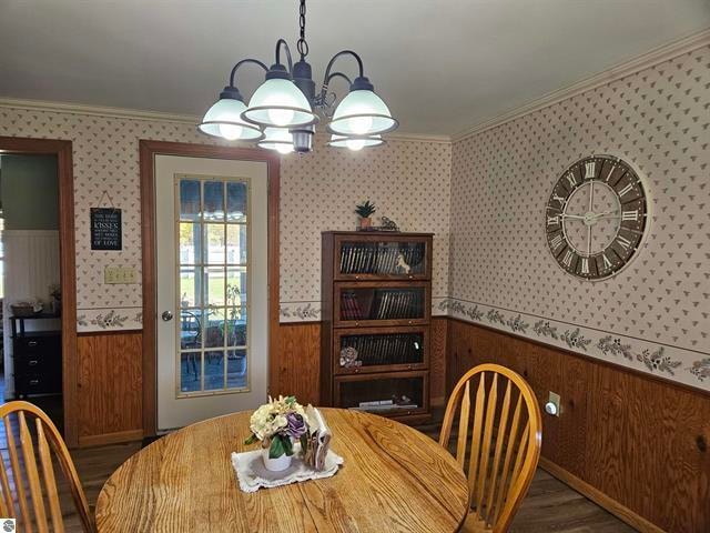 dining area with crown molding, a notable chandelier, and wood walls