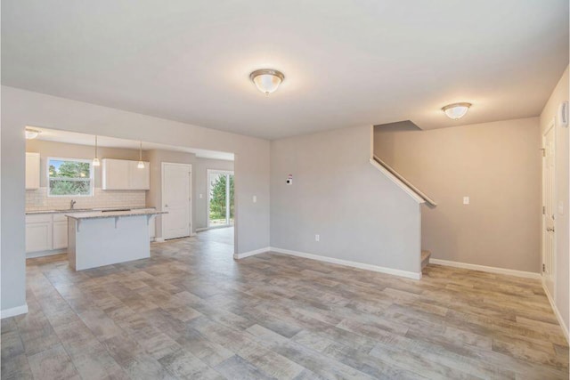 unfurnished living room featuring sink and light wood-type flooring