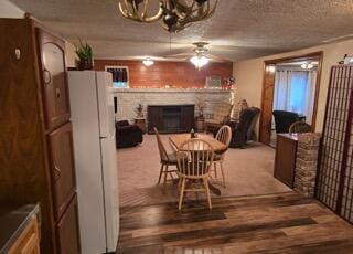 dining area with hardwood / wood-style floors, ceiling fan with notable chandelier, and a textured ceiling