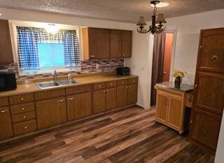 kitchen featuring backsplash, sink, dark hardwood / wood-style floors, a textured ceiling, and a notable chandelier