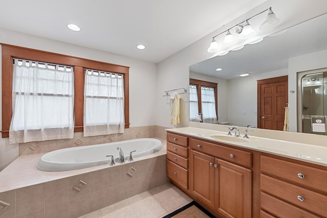 bathroom featuring vanity, tiled bath, and tile patterned flooring