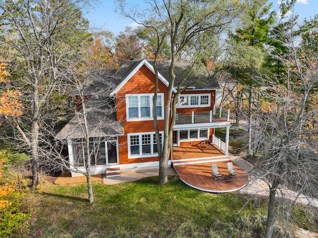 rear view of property with a sunroom, a deck, and a lawn