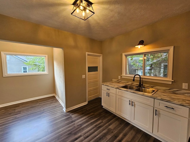 kitchen featuring light stone countertops, sink, a textured ceiling, white cabinets, and dark hardwood / wood-style floors