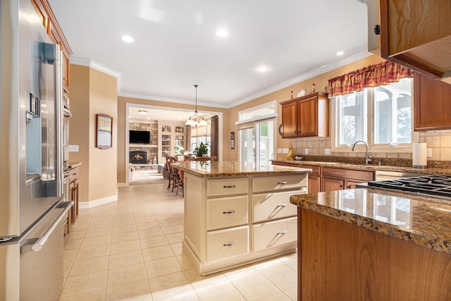 kitchen featuring tasteful backsplash, light tile patterned floors, stone countertops, pendant lighting, and crown molding