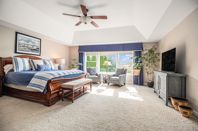 carpeted bedroom featuring a tray ceiling and ceiling fan