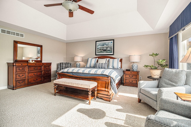 carpeted bedroom with a tray ceiling and ceiling fan