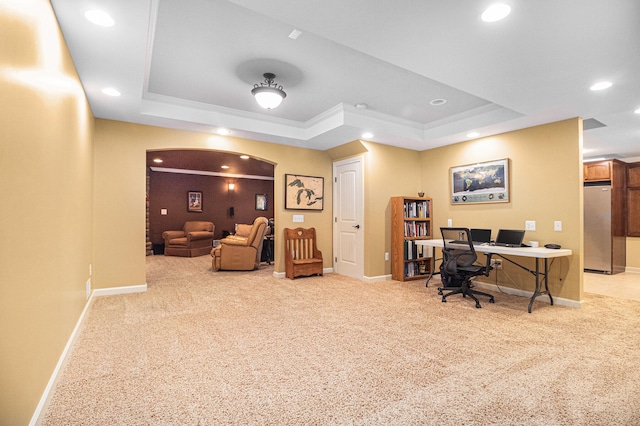 home office with ornamental molding, light colored carpet, and a tray ceiling