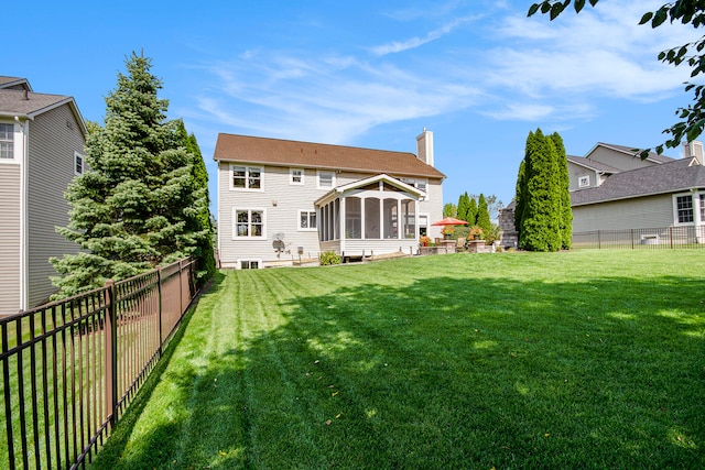 rear view of house featuring a yard and a sunroom