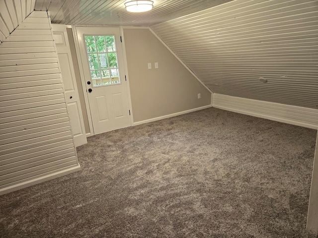 bonus room with vaulted ceiling and dark colored carpet