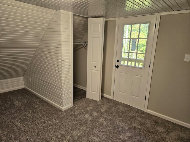 doorway featuring dark colored carpet, wood ceiling, and vaulted ceiling