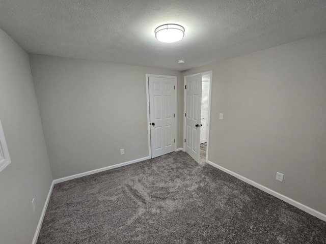 unfurnished room with a textured ceiling and dark carpet