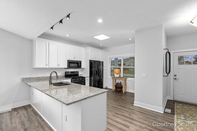 kitchen with sink, dark hardwood / wood-style flooring, kitchen peninsula, white cabinets, and black appliances