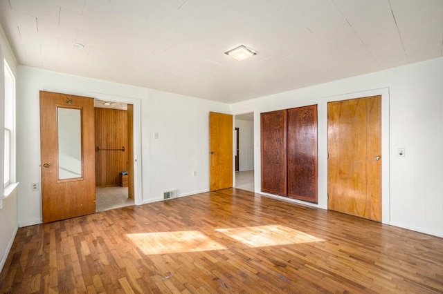 unfurnished bedroom with wood-type flooring and two closets