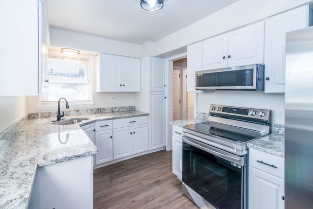 kitchen featuring white cabinets, light stone counters, appliances with stainless steel finishes, light hardwood / wood-style flooring, and sink