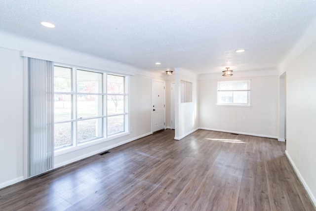 empty room featuring a textured ceiling and dark hardwood / wood-style floors