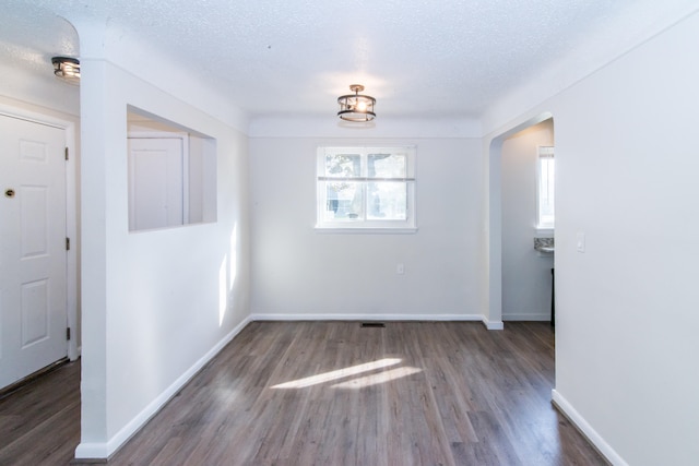 unfurnished dining area featuring dark wood-type flooring and a textured ceiling