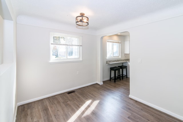 unfurnished room featuring a textured ceiling, a healthy amount of sunlight, and hardwood / wood-style flooring