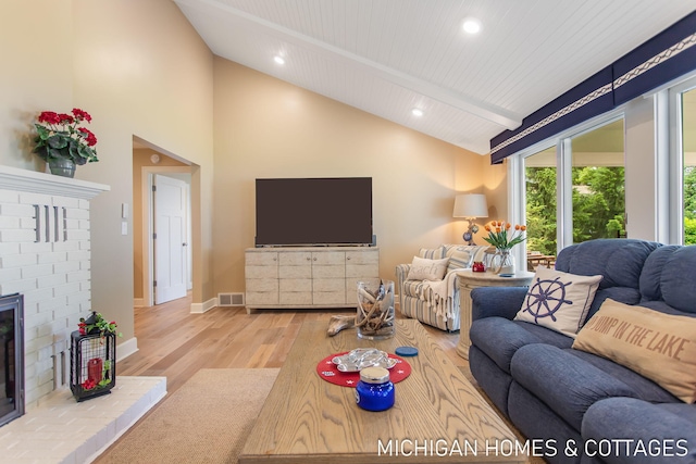 living room with wood ceiling, hardwood / wood-style floors, high vaulted ceiling, a brick fireplace, and beamed ceiling