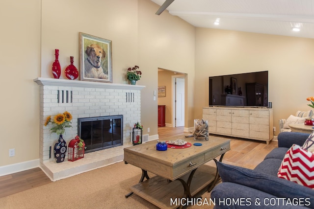 living room featuring high vaulted ceiling, beamed ceiling, wood-type flooring, and a brick fireplace