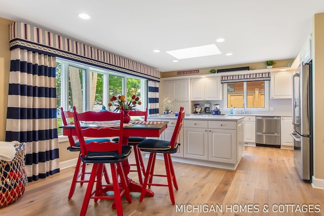 dining area featuring light hardwood / wood-style flooring and a skylight