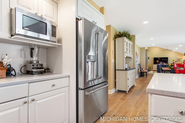 kitchen with white cabinets, stainless steel appliances, light wood-type flooring, and ceiling fan