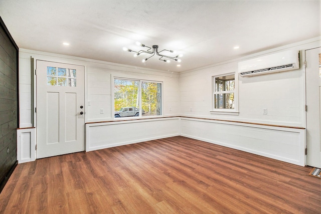 entrance foyer featuring ornamental molding, a wall mounted air conditioner, hardwood / wood-style flooring, and a textured ceiling