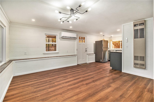 unfurnished living room featuring dark wood-type flooring, an inviting chandelier, and a wall unit AC